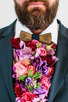 a bearded man wearing a suit and bow tie with flowers on it's lapel