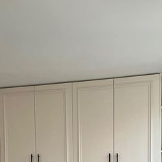 an empty kitchen with white cabinets and black counter tops, in the process of being painted