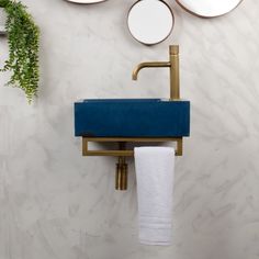 there is a blue towel hanging on the wall next to two mirrors and a gold faucet