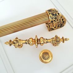 an ornate gold handle and curtain rod on a white surface with a golden door knob