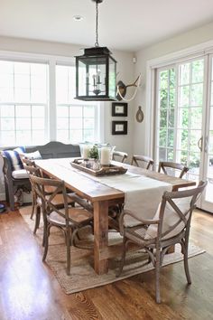 a dining room table and chairs in front of windows