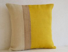 a yellow and brown striped pillow sitting on top of a white couch next to a wall