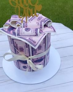 a birthday cake made out of money on top of a white table with grass in the background