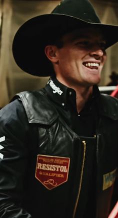 a man wearing a black hat and leather jacket