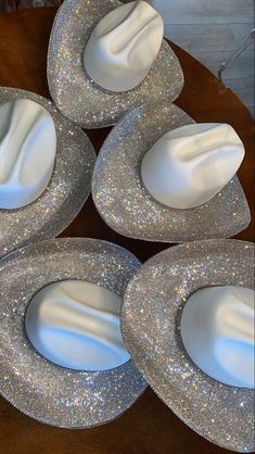 four shiny silver plates sitting on top of a wooden table next to another plate with white frosting