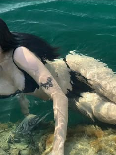 a woman is floating in the water with her body covered by black and white paint