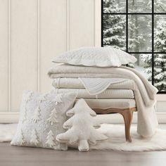 a pile of blankets and pillows sitting on top of a white rug next to a window