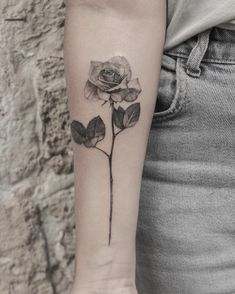 a woman's arm with a rose tattoo on the left side of her arm