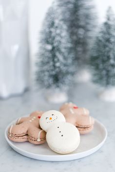 some cookies are sitting on a plate with snowmen in the backgroung