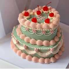 a three tiered cake with pink and green frosting, topped with cherries