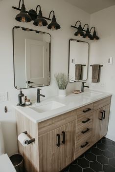 a bathroom with two sinks, mirrors and lights on the wall next to each other