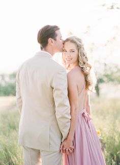 a man and woman standing next to each other in the middle of a grass field