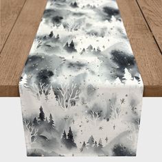 a table runner with trees and snow in the background on top of a wooden table