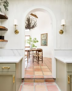 an archway leads to a dining room and kitchen with marble counter tops, tile flooring and gold accents