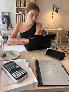 a woman sitting at a table with a laptop and calculator