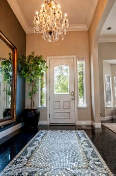 a chandelier hangs from the ceiling in front of a white door and entryway