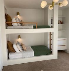 two bunk beds in a room with white walls and beige carpeting, one has green pillows on it