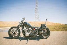 a motorcycle parked on the side of a road near a telephone pole and power lines