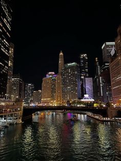 the city is lit up at night with lights reflecting in the water and skyscrapers