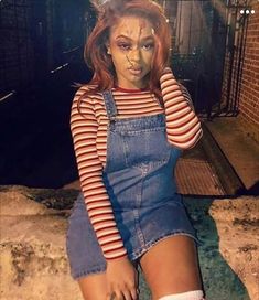 a woman in overalls and makeup sitting on the ground