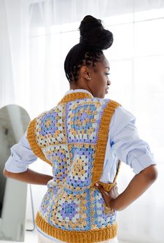 a woman with her back turned to the camera wearing a crocheted vest and white pants