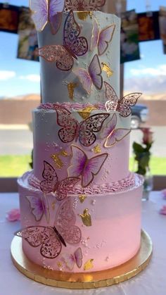 a three tiered cake with pink and gold butterflies on it