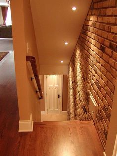 an empty room with wood flooring and brick wall in the corner, next to a white door