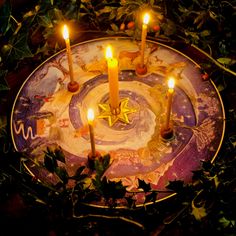 a plate with candles in the middle surrounded by greenery