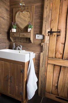 a bathroom with wooden walls and flooring, including a white sink in the center