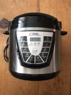 an electric pressure cooker on a wooden surface with the lid open and timers showing