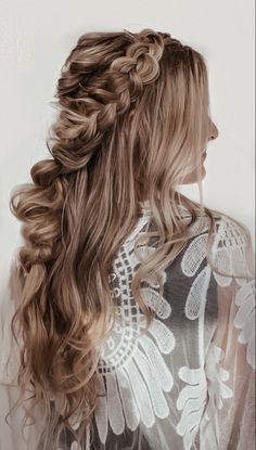 a woman with long hair wearing a white dress and braiding her hair in half - up