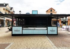 a food cart sitting on the side of a road next to buildings and people walking around