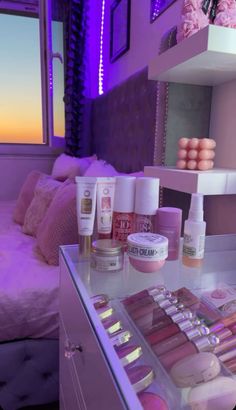 an assortment of beauty products displayed in front of a window at night with purple lighting