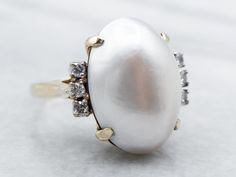 a pearl and diamond ring on a white surface