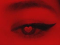 a woman's eye with a red heart in the middle of her irise