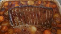 a roasting pan filled with meat, potatoes and carrots