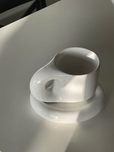 a white object sitting on top of a table next to a cup and saucer