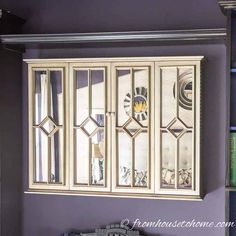 a wall mounted cabinet with mirrored doors and drawers in a room that has purple walls