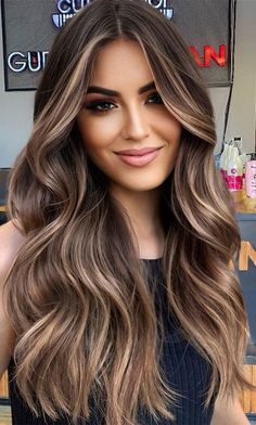 a woman with long, wavy hair is posing for a photo in front of a sign