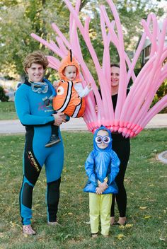 two adults and a child are standing in front of an inflatable tree