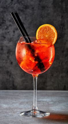 a drink with an orange slice and two black straws