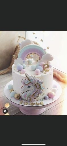 there is a white cake with a unicorn on it and rainbow decorations around the top