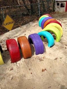 there are many different colored tires lined up in the sand