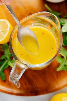 a person holding a spoon over a glass cup filled with liquid and garnished with fresh herbs