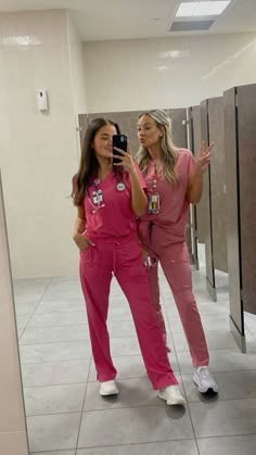 two women in pink scrubs are taking a selfie with their cell phone while standing next to each other