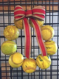 a wreath made out of baseballs with a red ribbon on it and some balls