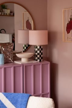 a room with a dresser, mirror and lamp on the sideboard next to it