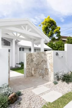 a white house with a stone wall in the front yard