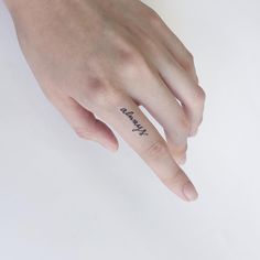 a person's hand with a small tattoo on the middle finger and an inscription that reads