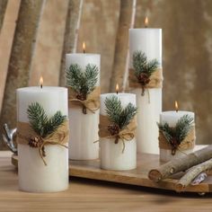 six white candles with pine cones and twine